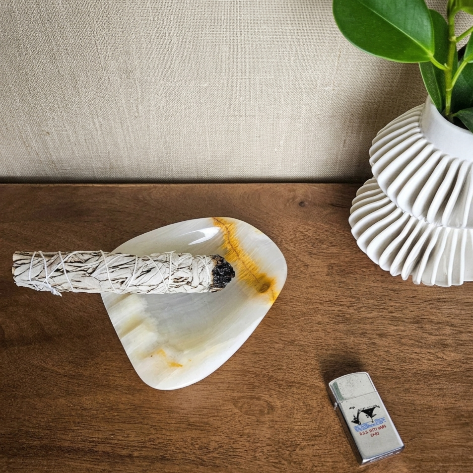 An organic, soft-cornered dish carved from translucent natural onyx featuring subtle creamy white banding, a warm caramel vein accent, and rest notches.