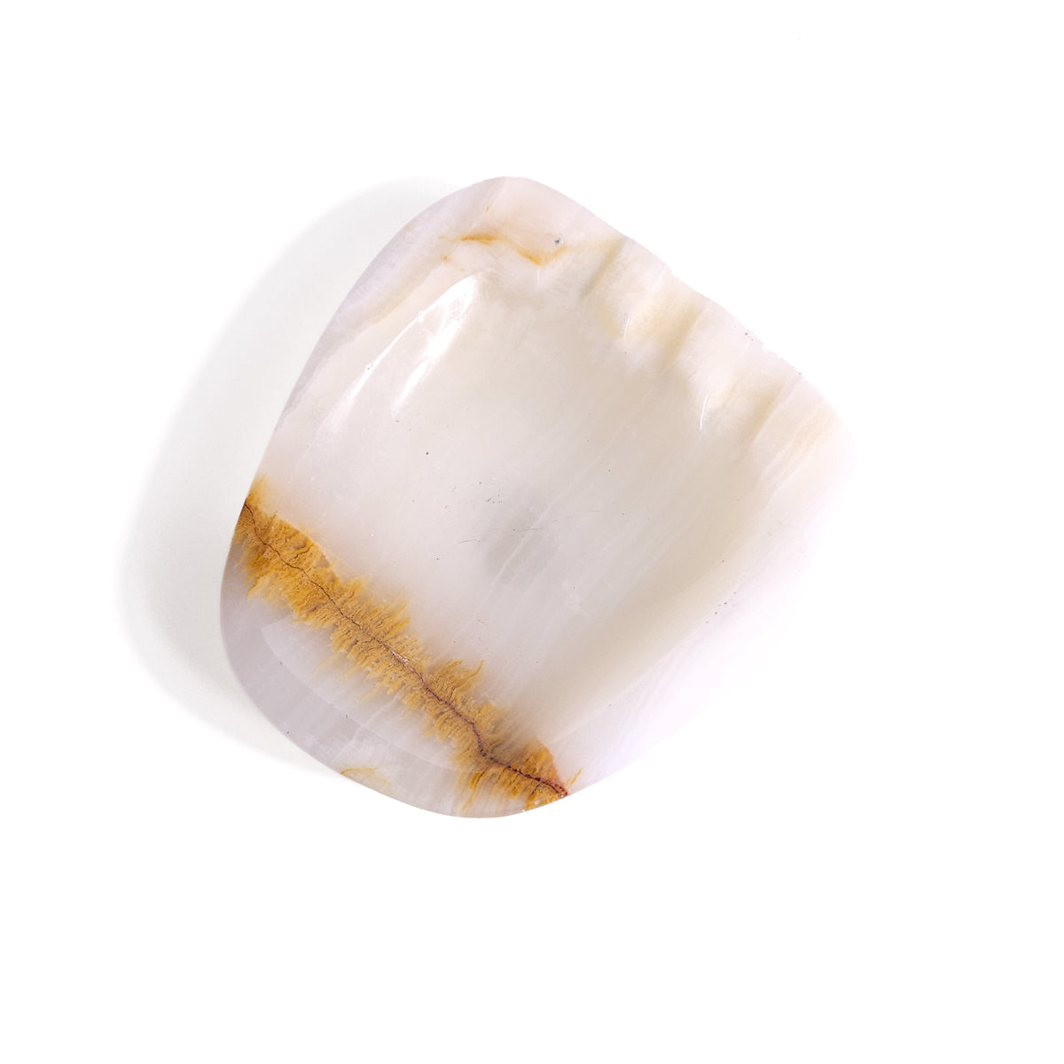 An organic, soft-cornered dish carved from translucent natural onyx featuring subtle creamy white banding, a warm caramel vein accent, and rest notches.