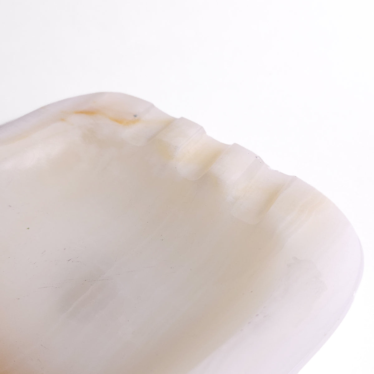 An organic, soft-cornered dish carved from translucent natural onyx featuring subtle creamy white banding, a warm caramel vein accent, and rest notches.
