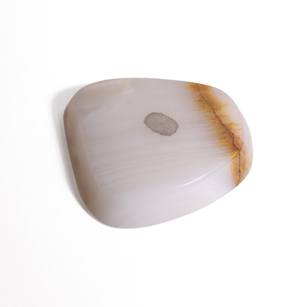 An organic, soft-cornered dish carved from translucent natural onyx featuring subtle creamy white banding, a warm caramel vein accent, and rest notches.